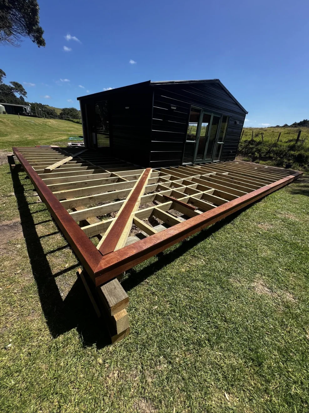 Large timber deck during framing around a black timber building